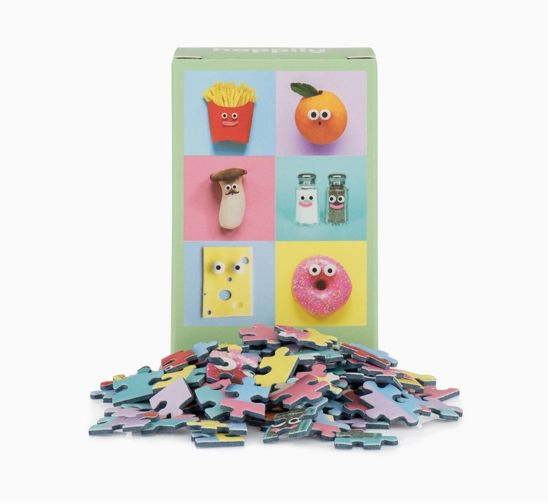 Puzzle set with colorful pieces and a box featuring cartoon food illustrations on a white background.